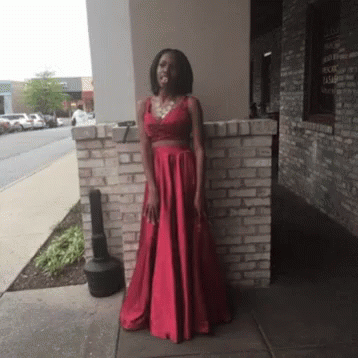 Woman in Red Dress Standing in Front of Brick Building