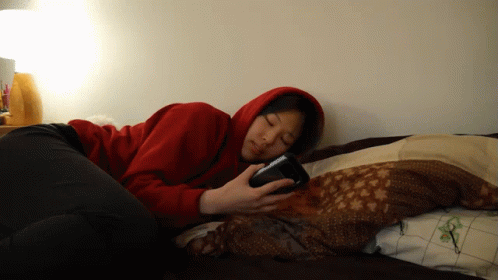 Woman in Red Hoodie on Phone in Bed