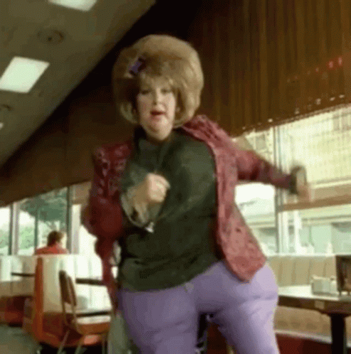 Woman in Red Jacket and Purple Pants Dancing in Restaurant