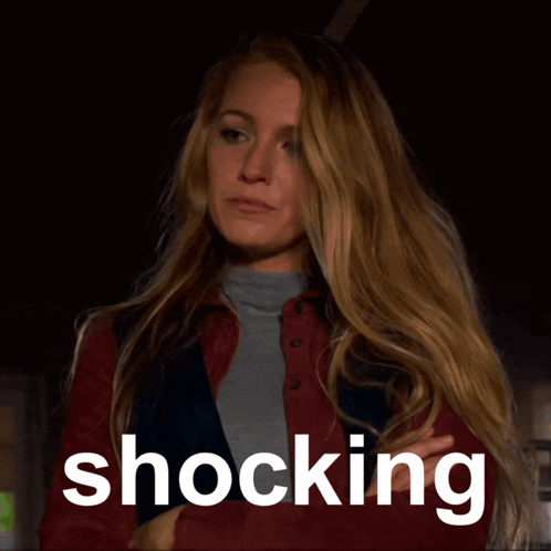 Woman in Red Jacket Standing Before Shocking Sign