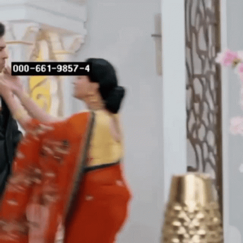 Woman in Red Saree Next to Man in Black Suit