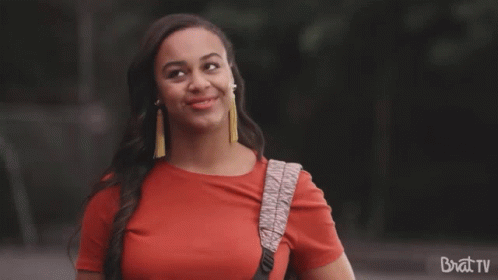 Woman In Red Shirt Smiling With Brat TV Backpack GIF