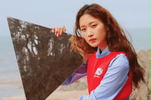 Woman in Red Sweater Holding Triangle in Front of Face