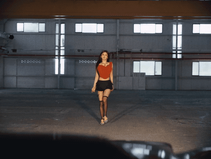 Woman in Red Top and Black Skirt Walking in Dark Room