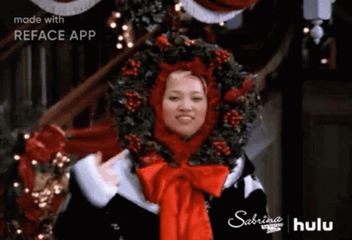 Woman In Santa Hat And Wreath With Christmas Tree GIF