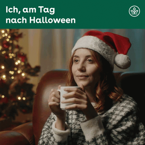 Woman In Santa Hat Sitting On Couch Holding Coffee GIF
