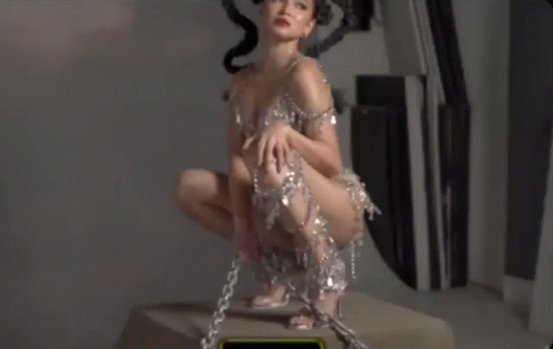 Woman In Short Dress Kneeling With Chains On Ankles GIF