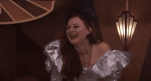 Woman in Silver Dress Laughing by Wall Light