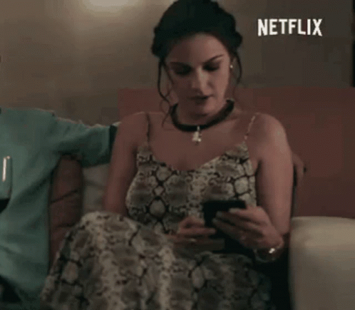 Woman in Snake Print Dress Looking at Phone on Couch Netflix