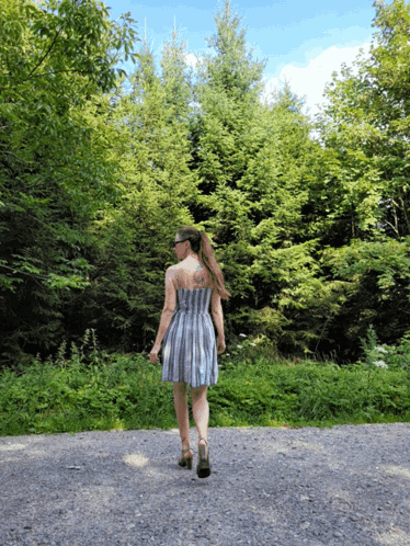 Woman in Striped Dress Walking Gravel Road
