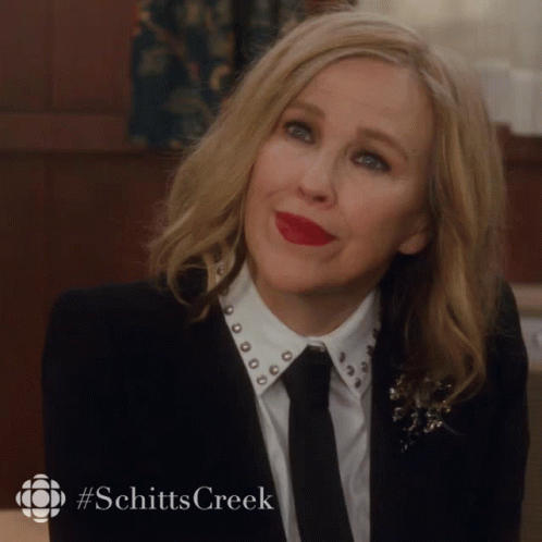 Woman In Suit And Tie With Schitts Creek Hashtag GIF