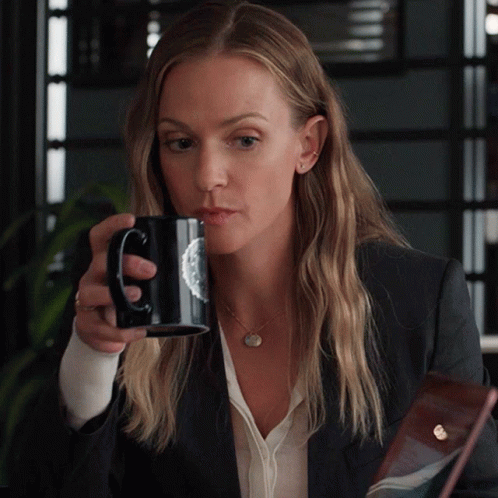 Woman in Suit Drinking From Black Mug With Circle