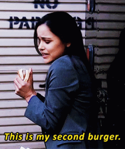 Woman In Suit Eating Burger Saying This Is My Second Burger GIF