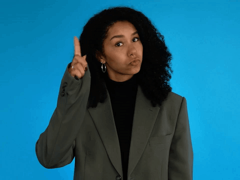 Woman In Suit Pointing Upward GIF
