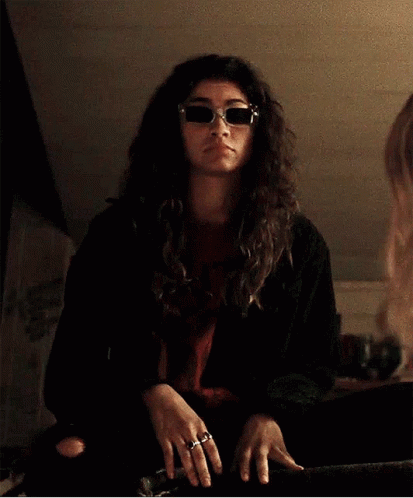 Woman in Sunglasses and Black Jacket Gesturing at Mirror