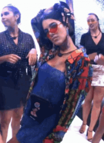 Woman in Sunglasses and Blue Dress Standing Next to Group of Women
