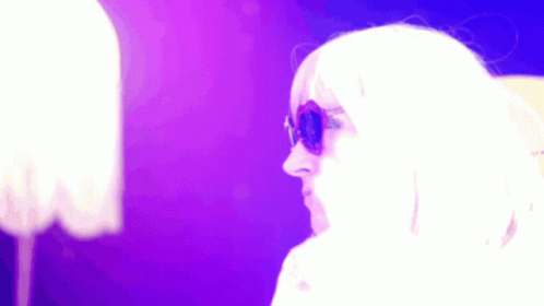 Woman in Sunglasses and White Wig Against Purple Background