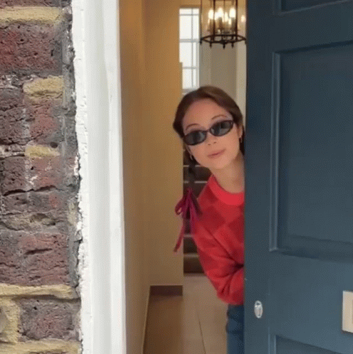 Woman in Sunglasses Peeking Out Door