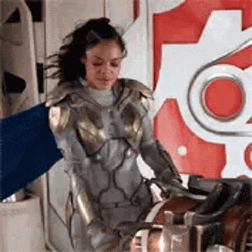 Woman in Superhero Costume Holding Blue Flag Next to Machine