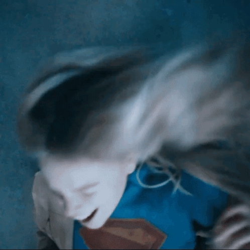 Woman In Superman Costume Laying Down Hair Blowing GIF