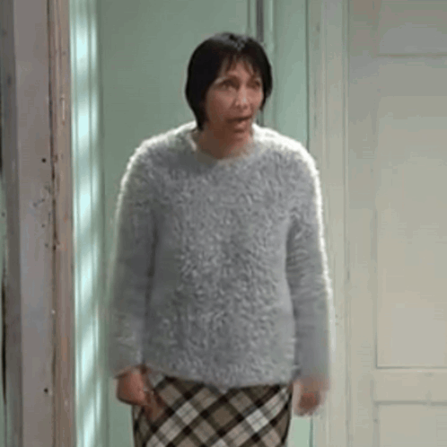 Woman in Sweater and Plaid Skirt Standing in Front of Door