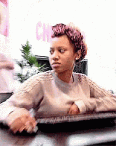 Woman in Sweater at Desk Looking at Camera