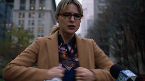 Woman In Tan Coat Speaking Into CBS Microphone GIF