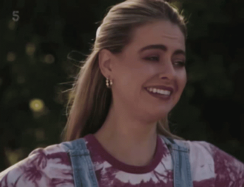 Woman in Tie Dye Shirt and Overalls Smiling With Number 5