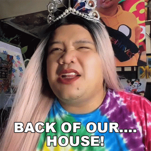 Woman In Tie Dye Shirt And Tiara Says Back Of Our House GIF