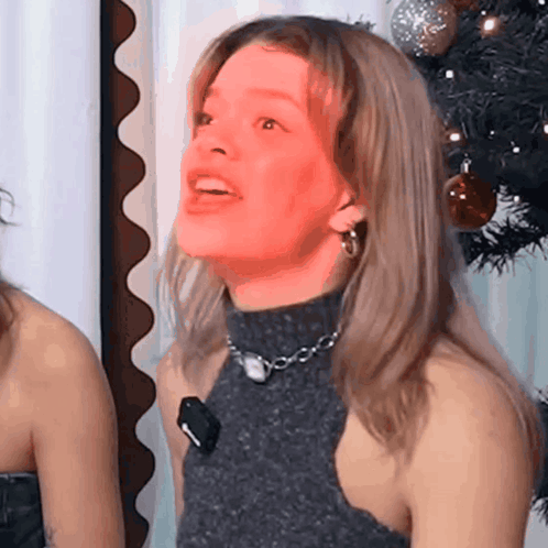 Woman in Turtleneck and Earrings Smiling with Christmas Tree