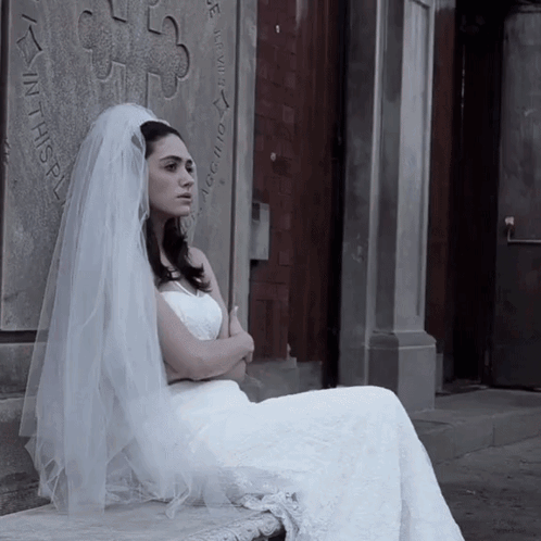 Woman in Wedding Dress Sitting in Front of Wall Saying In This