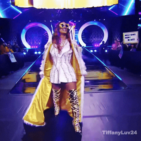Woman In White And Gold Outfit On Runway With Welcome Home Sign GIF