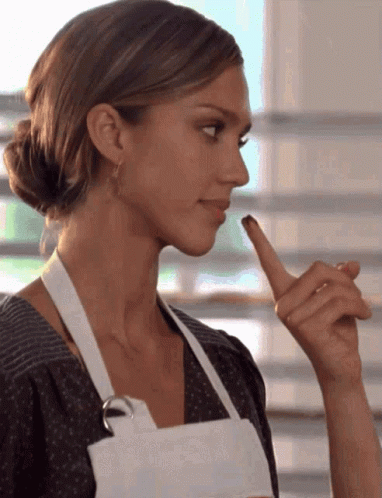 Woman in White Apron Holding Finger to Lips