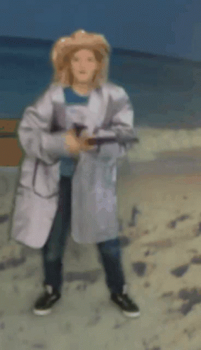Woman in White Coat and Straw Hat on Beach