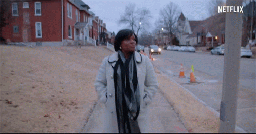 Woman in White Coat Walking Down Sidewalk With Netflix Logo