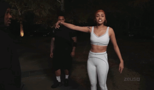 Woman In White Crop Top In Front Of Zeus Sign GIF