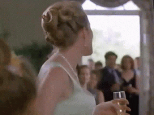 Woman in White Dress Holding Champagne Before Crowd