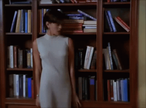 Woman in White Dress in Front of Bookshelf With Bible