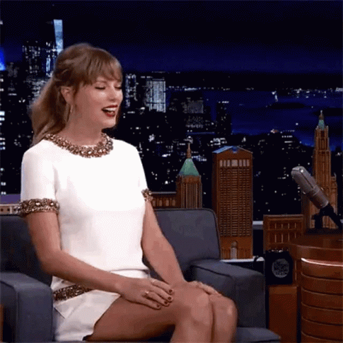 Woman in White Dress Sitting Cross-Legged and Laughing