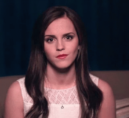Woman In White Dress Sitting On Couch Looking At Camera GIF