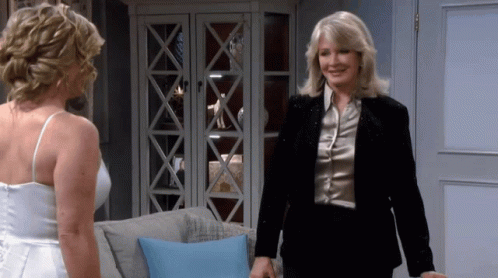 Woman In White Dress Standing Beside Woman In Black Suit GIF