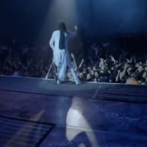 Woman in White Dress Walking Down Stage Before Crowd