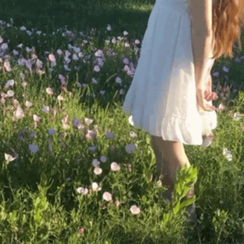 Woman In White Dress Walking Through Flower Field GIF