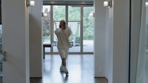 Woman in White Hoodie and Shorts Walking Hallway