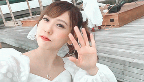 Woman in White Polka Dot Top Waving Hand