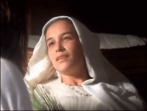 Woman In White Robe Laying In Bed Talking To Another Woman GIF