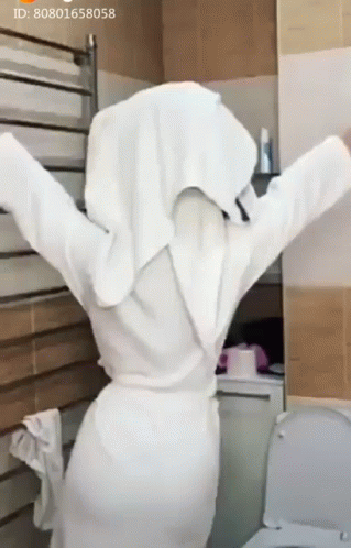 Woman In White Robe With Towel On Head In Front Of Toilet GIF