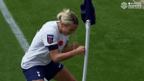 Woman in White Shirt and Blue Shorts Next to Flag