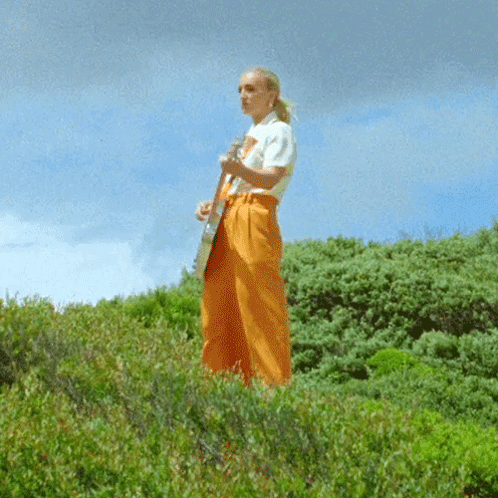 Woman in White Shirt and Orange Pants Playing Guitar