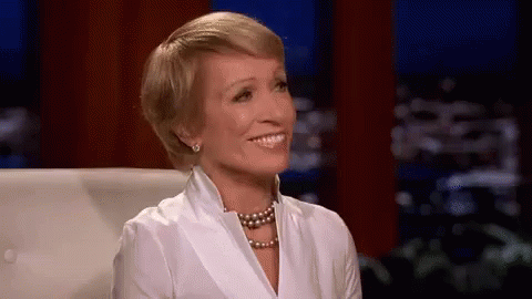 Woman In White Shirt And Pearl Necklace Smiling On Couch GIF